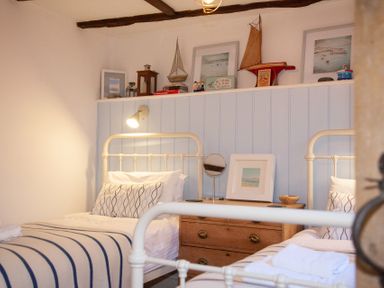 A bedroom with two single beds a wooden dresser and nautical decorations at The Sail Loft in St Ives
