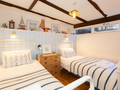 A bedroom with two single beds striped blankets and a wooden chest of drawers at The Sail Loft in St Ives