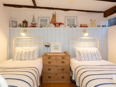 A bedroom with two single beds and a wooden chest of drawers between them at The Sail Loft in St Ives