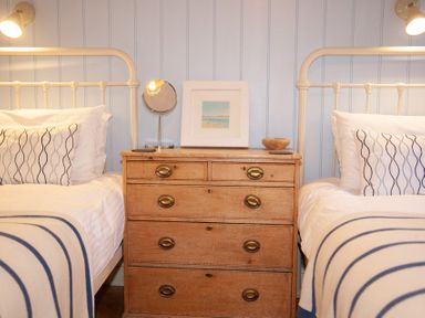 A bedroom with two single beds and a wooden chest of drawers between them at The Sail Loft in St Ives