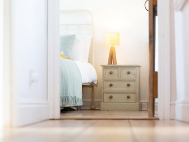A bedroom with a bed a nightstand with a lamp and a glass of orange juice at The Sail Loft in St Ives