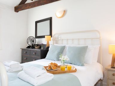 A bedroom with a bed with pillows and a tray with croissants and orange juice at The Sail Loft in St Ives