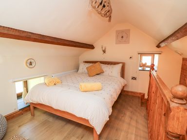 A bedroom with a wooden bed and two yellow towels on the bed at Tegfan Barn Pant-y-dwr near Rhayader