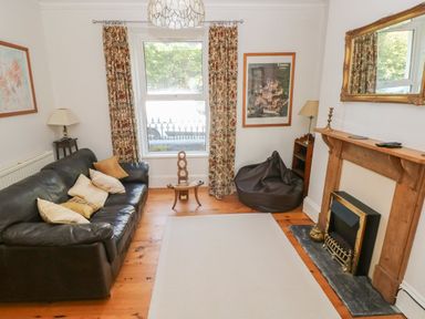 A living room with a leather sofa bean bag chair fireplace and window with curtains at Hawthorn House in Pembroke