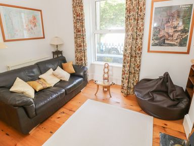 A sitting room with a leather sofa cushions bean bag chair and framed maps on the wall at Hawthorn House in Pembroke