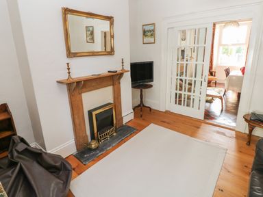 A sitting room with fireplace mirror flat screen tv and sliding glass doors at Hawthorn House in Pembroke