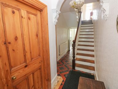 A hallway with a wooden door tiled floor and stairs with wooden handrail at Hawthorn House in Pembroke