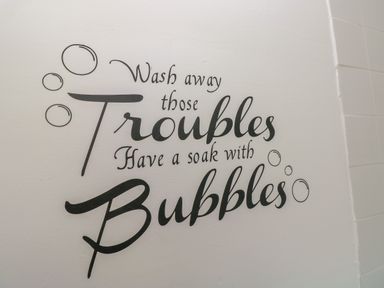 A wall with a quote about washing away troubles and soaking with bubbles in a bathroom at Hawthorn House in Pembroke