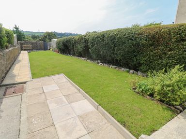 A garden with a lawn hedge along the side and a bench at the end at Hawthorn House in Pembroke