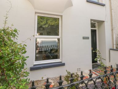 White exterior wall with a window and a black door with a sign reading Hawthorn House at Pembroke