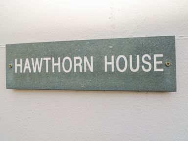A stone plaque with the text HAWTHORN HOUSE mounted on a white wall at Hawthorn House in Pembroke