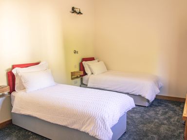 A bedroom with two single beds with white bedding and red headboards at Swallows Dip in Honiton