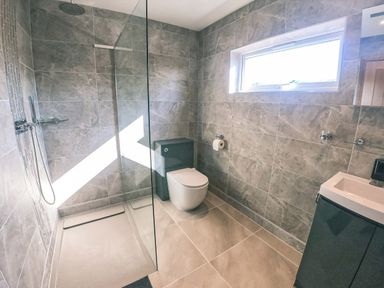 A bathroom with a walk in shower and a toilet next to a window at Swallows Dip in Honiton
