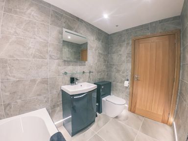 A bathroom with a sink cabinet mirror toilet bathtub and wooden door at Swallows Dip in Honiton