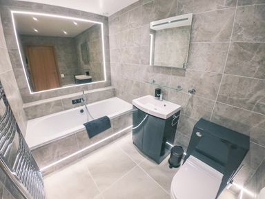 A bathroom with a bathtub a sink with a cabinet and a toilet at Swallows Dip in Honiton