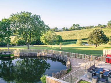 A garden with a pond trees picnic table barbecue and outdoor dining area at Swallows Dip in Honiton