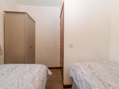 A small bedroom with two single beds and a wardrobe at Trem Y Wyddfa in Gaerwen