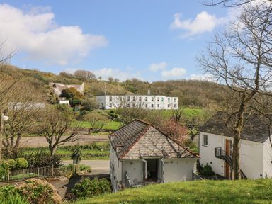 A view of white houses with pitched roofs surrounded by trees and greenery in a rural area at Longships in Porthcurno