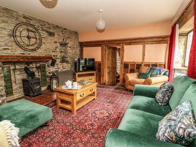 A living room with green sofa armchair wooden coffee table and stone walls at Pant Y Rhedyn in Abbeycwmhir near Rhayader
