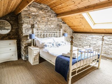 A bedroom with a metal bed frame a chest of drawers and a skylight window at Pant Y Rhedyn in Abbeycwmhir near Rhayader