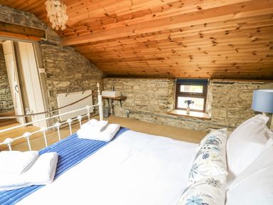 A bedroom with a bed a small window a wall-mounted sink and a wooden ceiling at Pant Y Rhedyn in Abbeycwmhir near Rhayader
