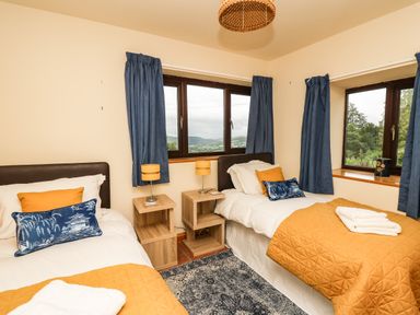 A bedroom with two single beds bedside tables and blue curtains at Pant Y Rhedyn in Abbeycwmhir near Rhayader