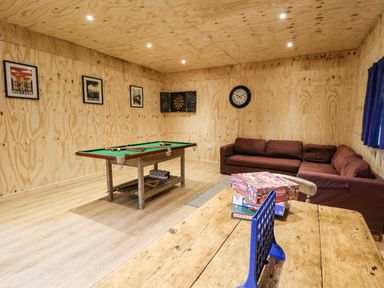 A game room with a pool table sofa and board games on a wooden table at Pant Y Rhedyn in Abbeycwmhir near Rhayader