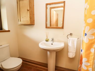 A bathroom with a toilet sink mirror and a towel next to a yellow shower curtain at Pant Y Rhedyn in Abbeycwmhir near Rhayader