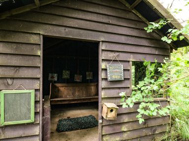 A wooden shed with an open door showing a wooden bench a small blue rug and drawing boards hanging inside Pant Y Rhedyn Abbeycwmhir near Rhayader