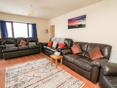 A living room with three leather sofas a small wooden table with a bowl a floor lamp and a painting on the wall at Pant Y Rhedyn in Abbeycwmhir near Rhayader