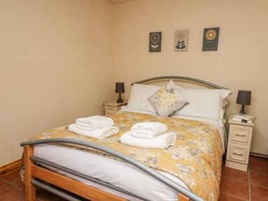 A bedroom with a double bed with folded towels on it and two bedside tables with lamps at Pant Y Rhedyn in Abbeycwmhir near Rhayader