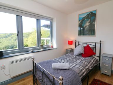 A bedroom with a single bed next to a window overlooking greenery at Higher Bumsley Barn in Parracombe