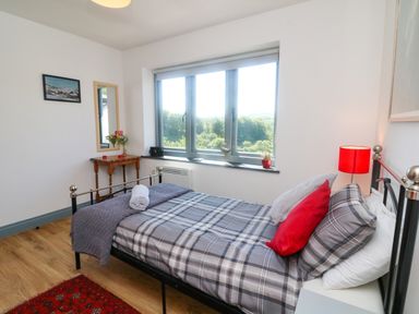 A bedroom with a single bed next to a window and a small wooden table with a mirror at Higher Bumsley Barn in Parracombe