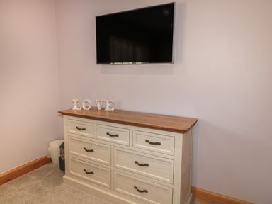 A dresser with decorative letters spelling love and a wall mounted television above at Treetops in Otterburn