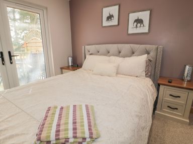 A bedroom with a bed and striped towel on it beside bedside tables with lamps at Treetops in Otterburn
