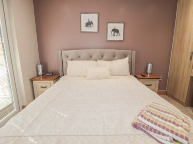 A bedroom with a bed and pillows bedside tables with lamps and a folded blanket at Treetops in Otterburn
