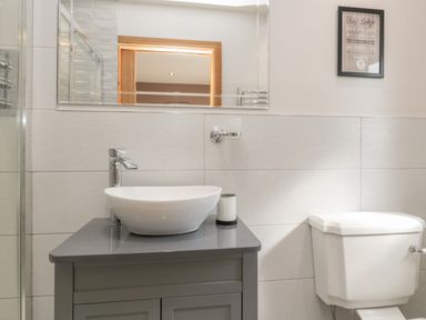 A bathroom with a white vessel sink on a gray cabinet a toilet and a framed sign on the wall at Treetops in Otterburn