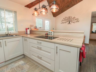 A kitchen with a countertop, built-in stove, sink, cabinets, pendant lights, and a wall decoration at Treetops in Otterburn