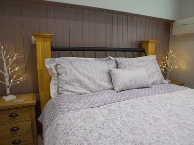A bed with patterned bedding and pillows with wooden posts and bedside tables with decorative light trees at Treetops in Otterburn