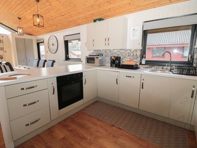 A kitchen with cabinets oven microwave coffee maker and sink at Pine Tree in Otterburn