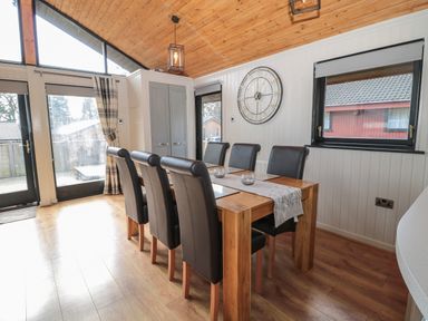 A dining room with a wooden table and six black chairs at Pine Tree in Otterburn