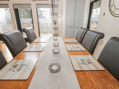 A dining table with six leather chairs placemats and candle holders at Pine Tree in Otterburn