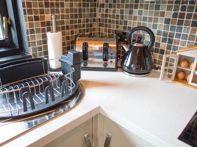 A kitchen corner with a toaster kettle dish rack paper towel and an egg holder with eggs at Pine Tree in Otterburn