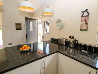 A kitchen counter with a bowl of fruit a toaster an electric kettle and canisters labeled tea sugar and coffee at Broken-Sky Lodge in Otterburn