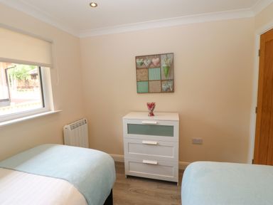 A bedroom with two single beds a white chest of drawers and a window at Broken-Sky Lodge in Otterburn