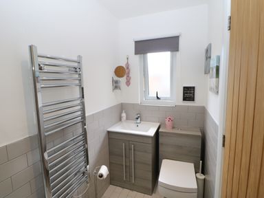 A small bathroom with a toilet sink vanity and heated towel rail at Broken-Sky Lodge in Otterburn