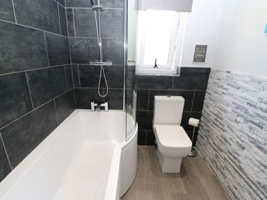 A bathroom with a bathtub shower combination and a toilet at Broken-Sky Lodge in Otterburn