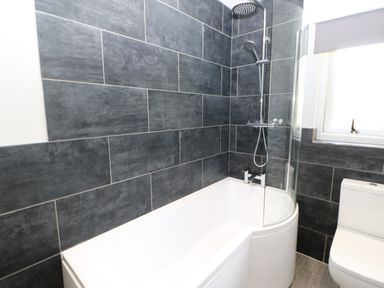 A bathroom with a bathtub a showerhead and a toilet at Broken-Sky Lodge in Otterburn