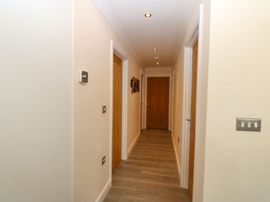 A hallway with wooden doors on both sides wooden floor and ceiling lights at Broken-Sky Lodge in Otterburn