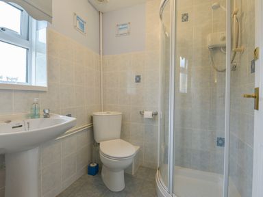 A bathroom with a toilet sink and corner shower at Broadclyst Cottage in Ottery St Mary